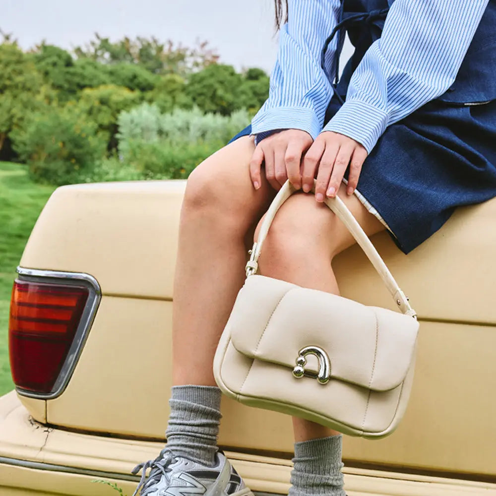 Woman holding cream handbag on vintage car, Amazing Song brand fashion accessory outdoors