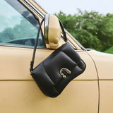 Black leather handbag with metal clasp on vintage beige car door, Amazing Song style