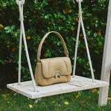 Beige leather handbag on wooden swing, Amazing Song official product, garden background