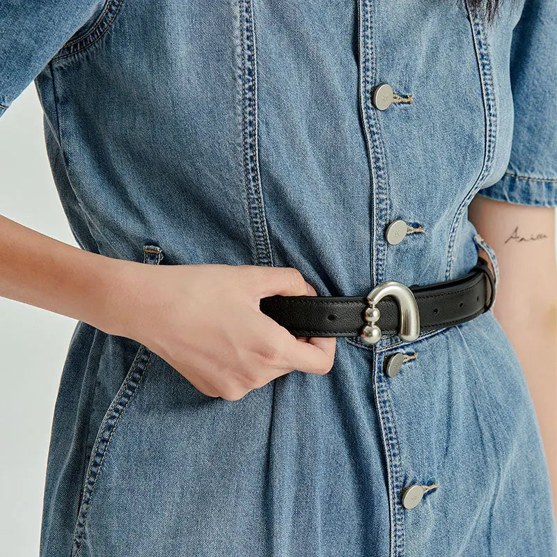 Close-up of a woman wearing a denim dress with a black belt and silver buckle, Amazing Song fashion.