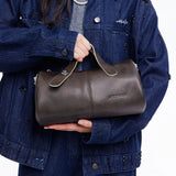 Woman in denim jacket holding an Amazing Song dark brown leather handbag