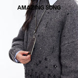 Woman in gray sweater holding black lanyard card holder, Amazing Song branding visible