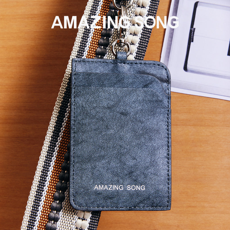 Amazing Song branded blue leather card holder on striped fabric strap, wooden surface background
