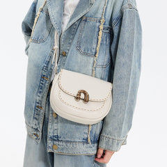 White crossbody handbag with gold clasp on denim jacket, Amazing Song fashion accessory