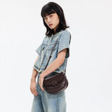 Woman in light denim outfit modeling a dark brown crossbody bag, Amazing Song brand