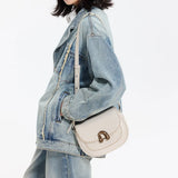 Woman in denim jacket and jeans with a cream leather shoulder bag, Amazing Song style
