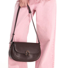 Brown leather shoulder bag with metal clasp, held by a person in pink jeans, Amazing Song