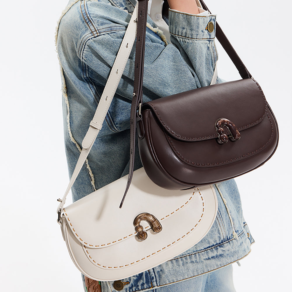 Person in denim jacket carrying brown and white Amazing Song handbags with buckle detail