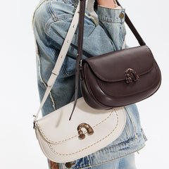 Person in denim jacket carrying brown and white Amazing Song handbags with buckle detail