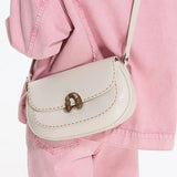 Cream leather shoulder bag with gold clasp, styled over light pink denim jacket and pants