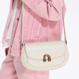 Cream leather crossbody bag with gold clasp, worn over a pink denim jacket and pants