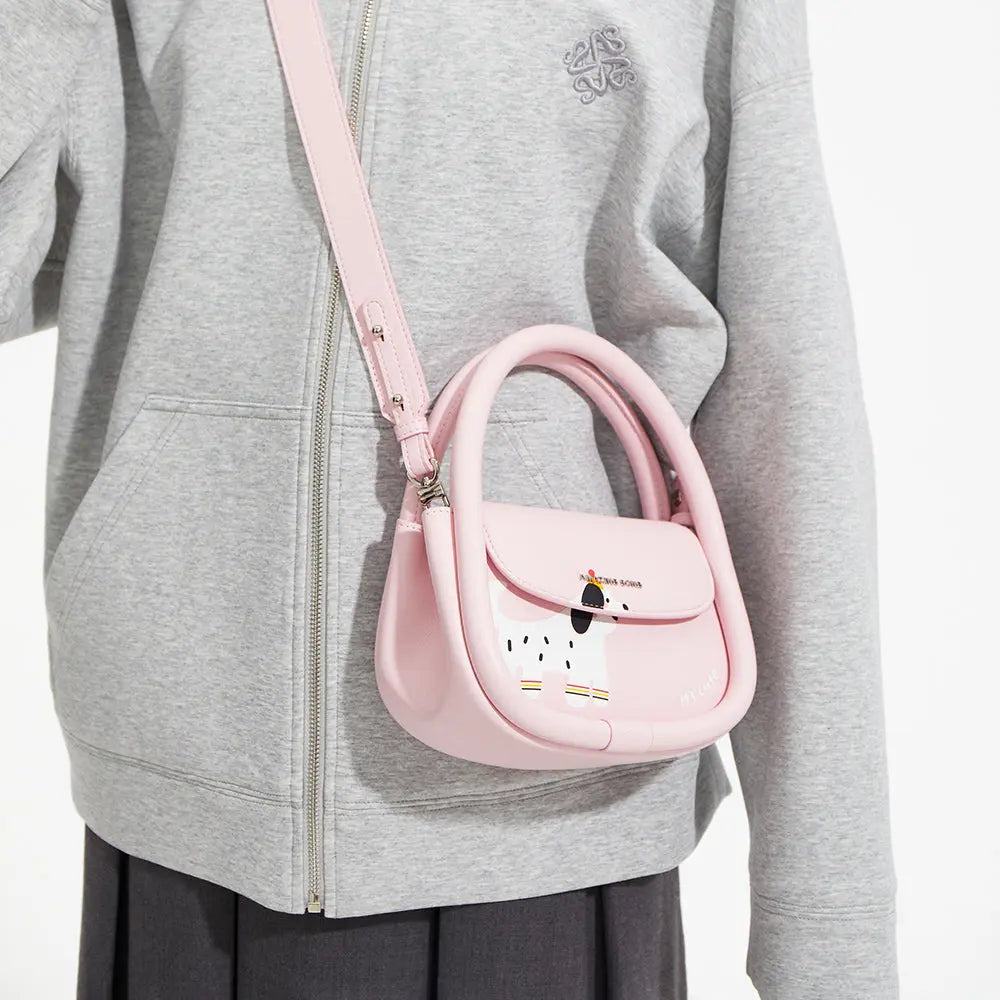 Person in grey jacket wearing a pink Amazing Song crossbody bag with cartoon dog design