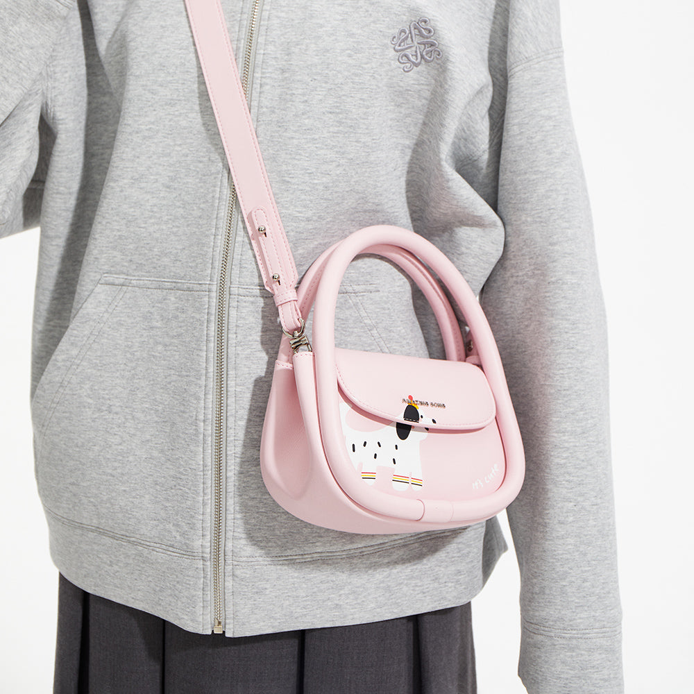 Person in grey jacket wearing a pink Amazing Song crossbody bag with cartoon dog design