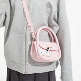 Person in grey jacket wearing a pink Amazing Song crossbody bag with cartoon dog design