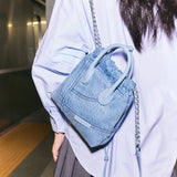 Woman with light blue denim handbag and chain strap at a subway platform, Amazing Song style