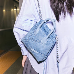 Woman with light blue denim handbag and chain strap at a subway platform, Amazing Song style