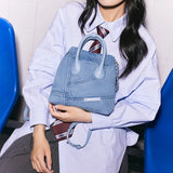 Woman in blue shirt holding Amazing Song denim handbag on lap, seated on blue chair