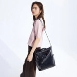Woman in light pink top carrying large black leather shoulder bag, Amazing Song style