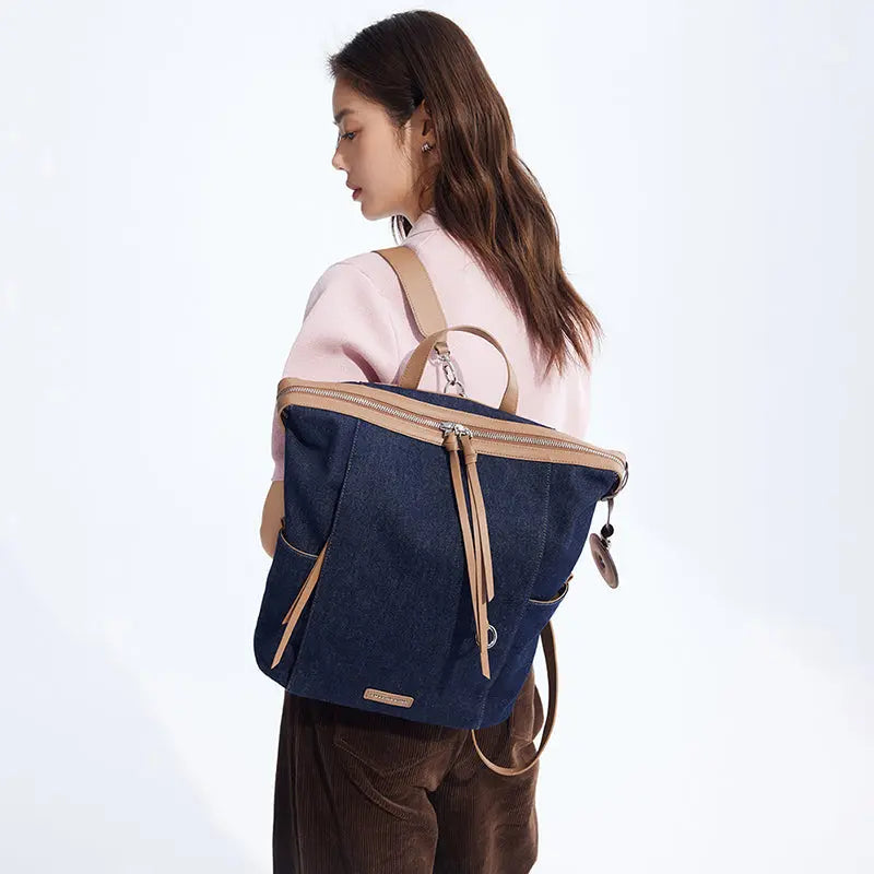 Woman in pink sweater carrying navy denim and tan leather backpack, Amazing Song style.