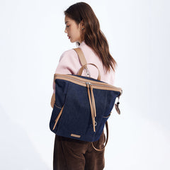 Woman in pink sweater carrying navy denim and tan leather backpack, Amazing Song style.