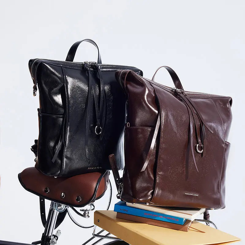 Amazing Song leather backpacks in black and brown on a bike seat with books, official website
