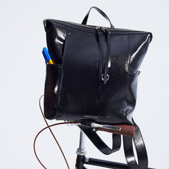 Amazing Song black leather backpack on bicycle seat with pens in pocket