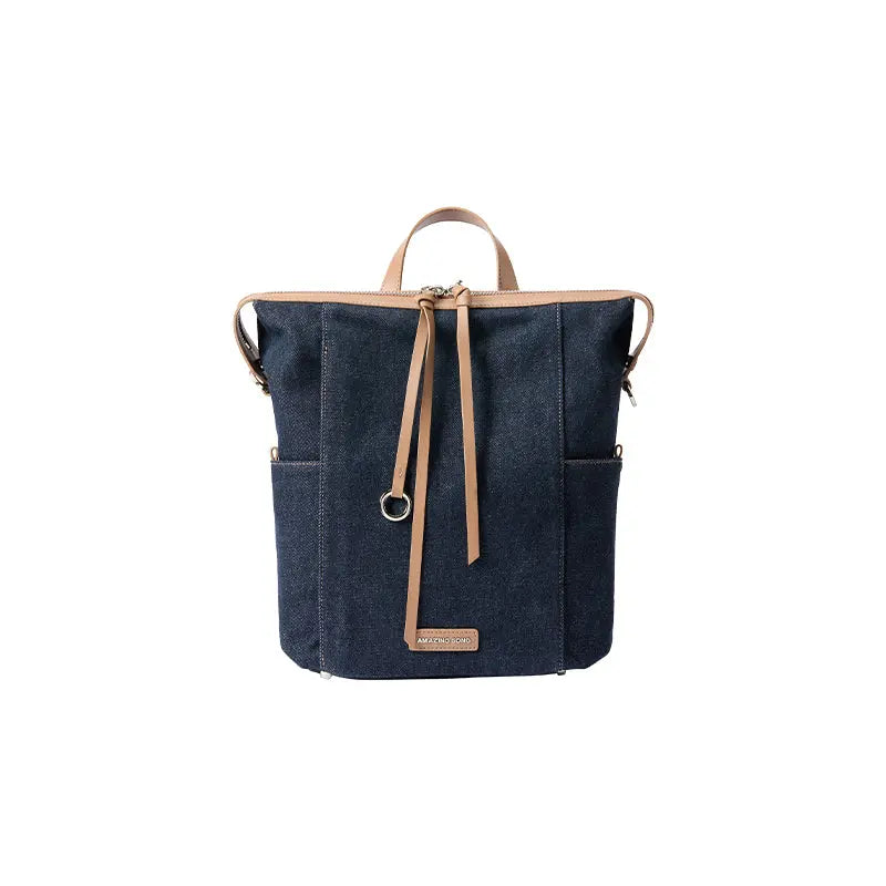 Dark blue denim tote backpack with tan leather straps, Amazing Song logo on front, white background
