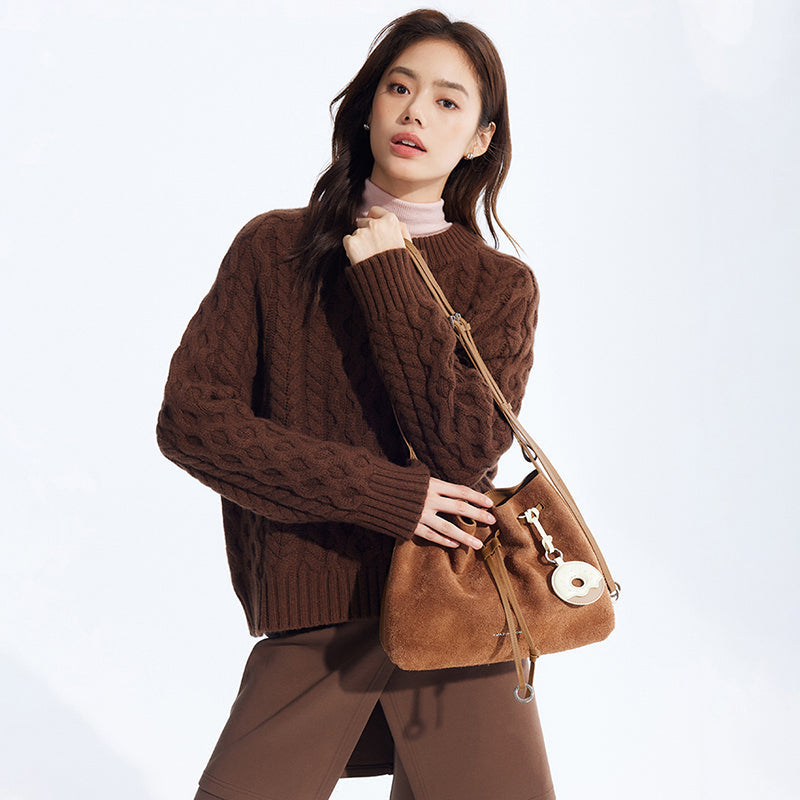 Woman in brown cable-knit sweater holding tan suede shoulder bag, Amazing Song official website