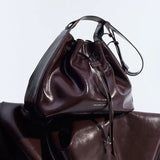 Shiny dark brown leather handbag with drawstring closure and 'Amazing Song' branding