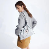 Woman wearing grey blazer and tan skirt with Amazing Song light blue handbag