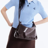 Woman wearing blue knit top and brown skirt with dark brown Amazing Song shoulder bag
