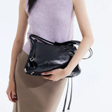 Woman holding glossy black handbag, Amazing Song fashion accessory, beige skirt, lavender top