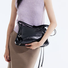 Woman holding glossy black handbag, Amazing Song fashion accessory, beige skirt, lavender top