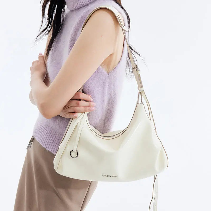 Woman wearing sleeveless lavender sweater with cream Amazing Song shoulder bag