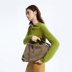 Woman in green sweater holding stylish taupe handbag, Amazing Song fashion accessory