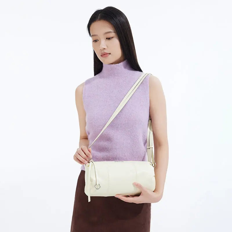 Woman in a lavender sleeveless top holding a cream shoulder bag, Amazing Song style