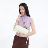 Woman in lilac sleeveless top and brown skirt holding a cream shoulder bag, Amazing Song