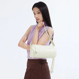 Woman in lavender sleeveless top holding cream shoulder bag, Amazing Song official website
