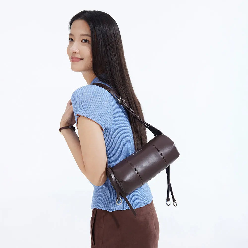 Woman in blue top with brown leather shoulder bag, Amazing Song official website