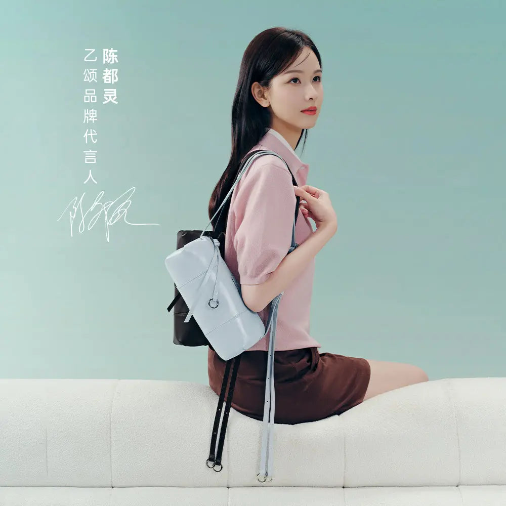 Woman with light blue backpack sitting on white sofa, pastel background, Amazing Song