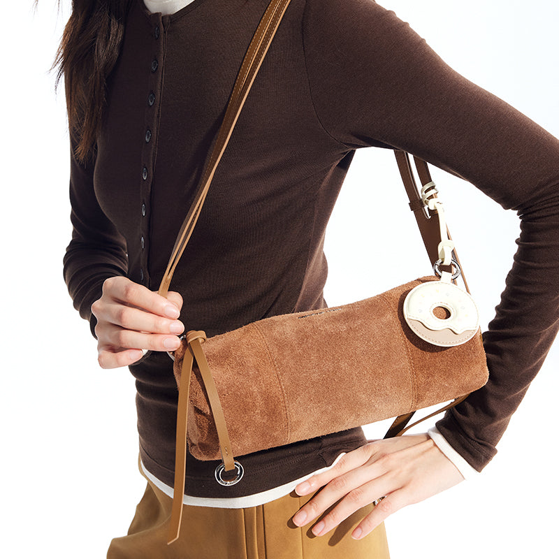 Woman wearing brown top and holding brown suede crossbody bag, Amazing Song official website