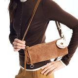 Woman wearing brown top and holding brown suede crossbody bag, Amazing Song official website