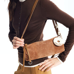 Woman wearing brown top and holding brown suede crossbody bag, Amazing Song official website