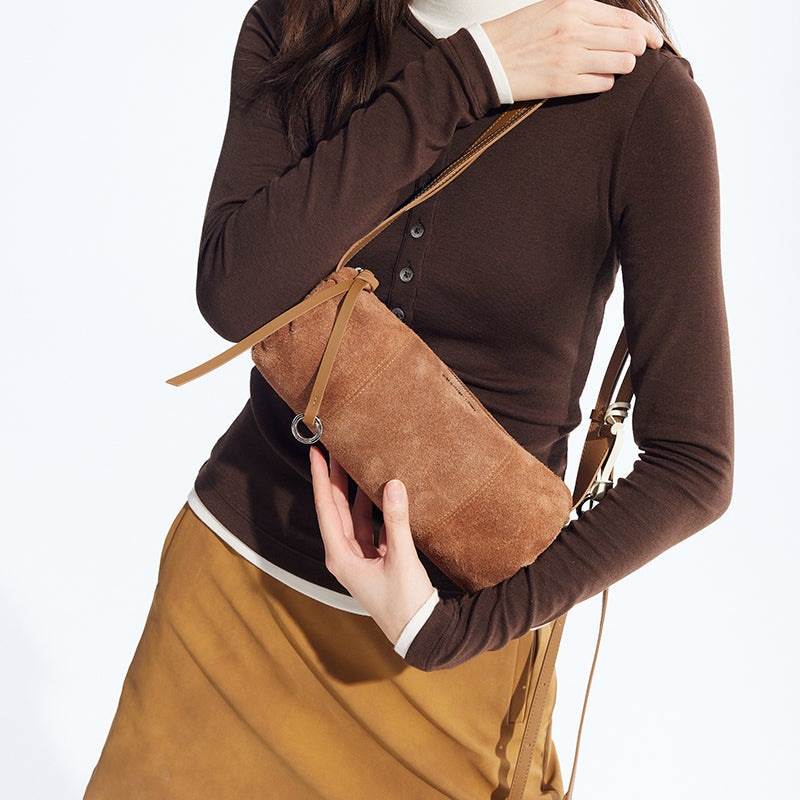 Woman holding suede brown shoulder bag, wearing brown top and camel skirt from Amazing Song