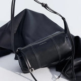 Amazing Song black leather crossbody bag with silver zipper and strap detail on fabric backdrop