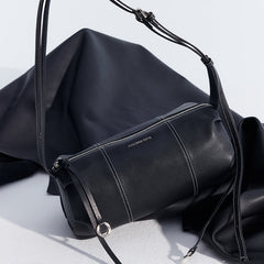 Amazing Song black leather crossbody bag with silver zipper and strap detail on fabric backdrop