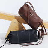 Amazing Song black and brown leather shoulder bags on light wood stand, minimalist style