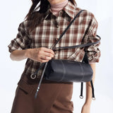 Woman in plaid shirt with Amazing Song black leather crossbody bag