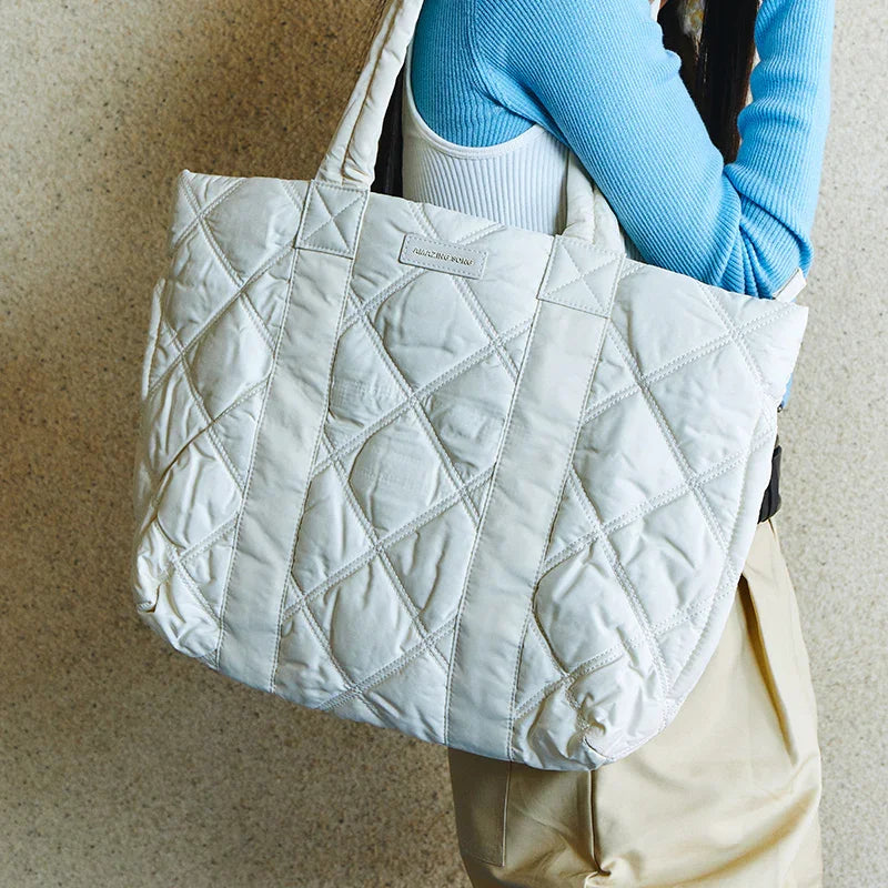 Quilted white tote bag with diamond stitches, Amazing Song label, carried by person in blue top