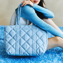Woman holding large quilted light blue tote bag on blue shag carpet, Amazing Song